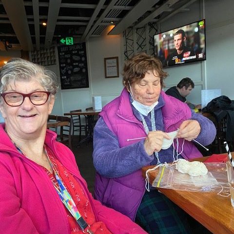 Yarn Circle members knitting a scarf at disability social group